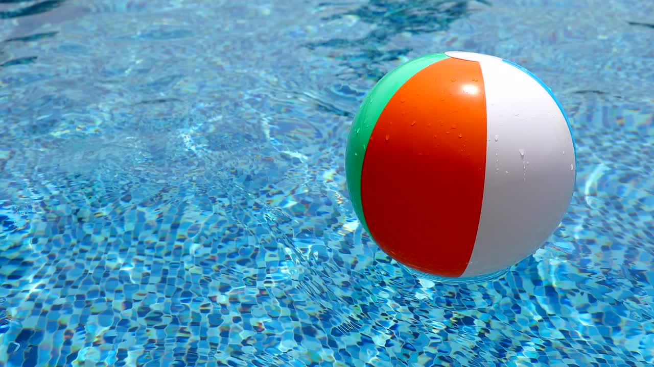 Beach ball in pool. Colorful inflatable ball floating in swimming pool, summer vacation concept.