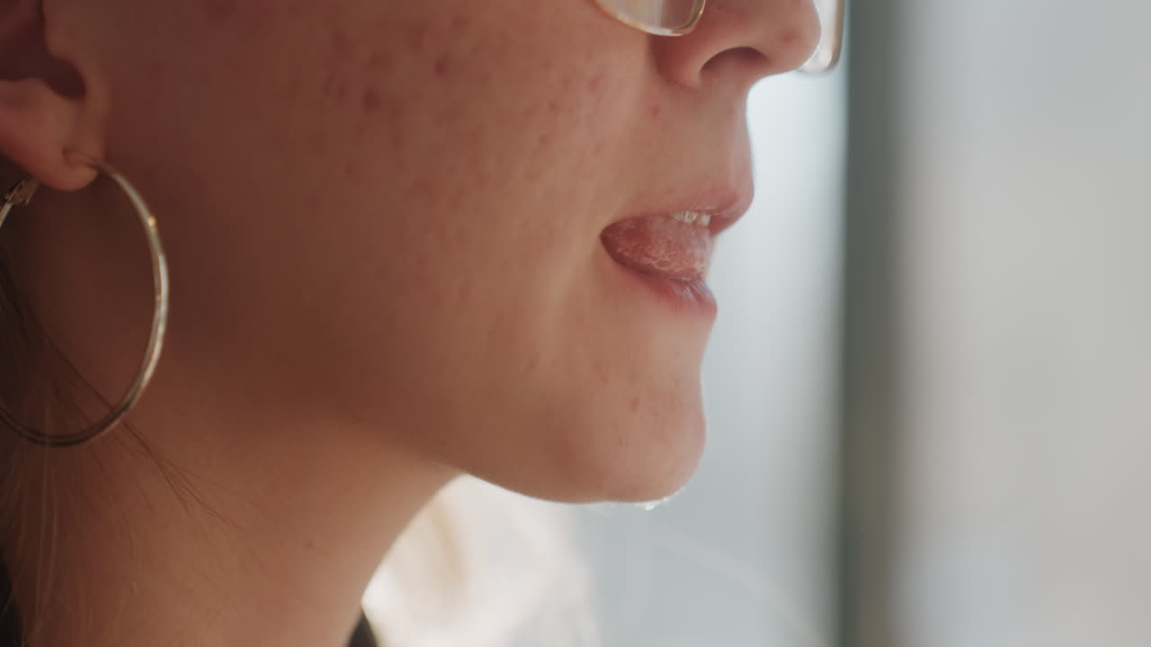 Sorriso mattutino sereno. Una donna soddisfatta si gode una bevanda al sole. Una donna serena sorride vicino alla delicata luce solare che filtra dalla finestra. Una donna tranquilla si rilassa pacificamente accanto a una bevanda calda nella morbida luce del mattino.