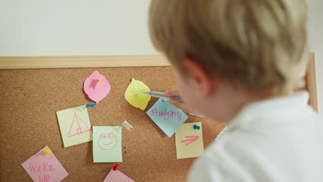 preschooler draws sun with pen on leaf of colored paper