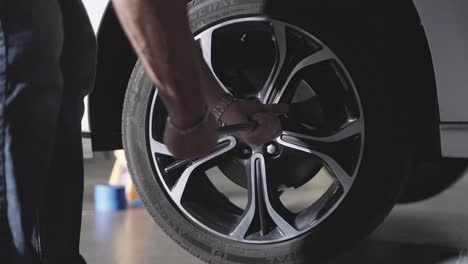 unrecognizable mechanic using lug wrench to remove lug nuts from car wheel, slow motion