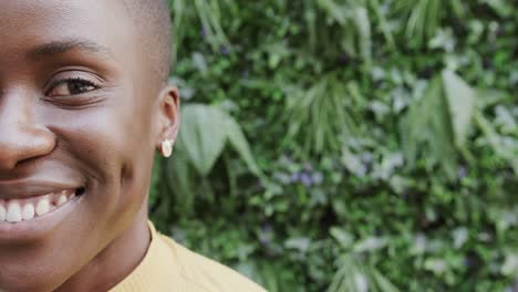 Half-portrait-of-happy-african-american-woman-smiling-in-front-of-plants,-copy-space,-slow-motion