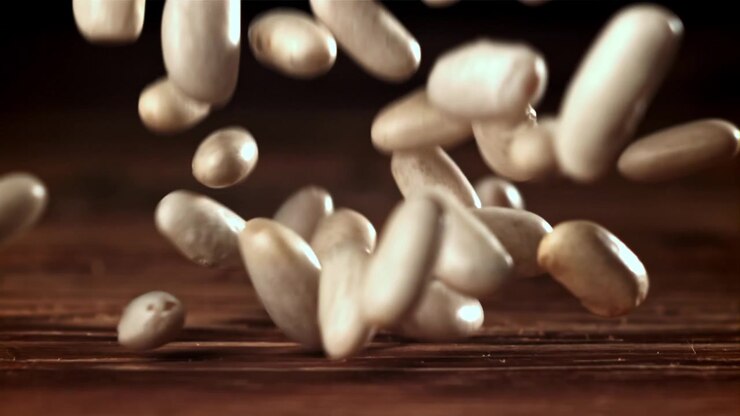 White Beans Falling in Slow Motion onto a Wooden Surface