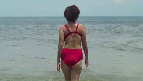 The-allure-of-a-tropical-beach-is-heightened-as-a-Latina-beauty,-with-curly-hair,-rocks-a-sexy-bikini-with-confidence