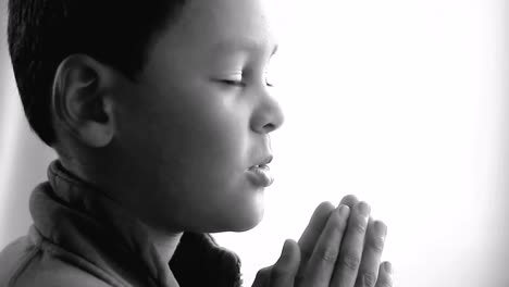 little-boy-praying-to-God-with-hands-together-on-white-background-with-people-stock-video-stock-footage