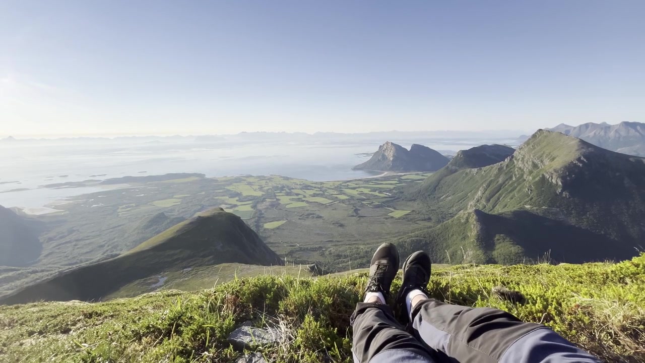 Lofoten hiker crossing feet in front of majestic coastal view in sunshine