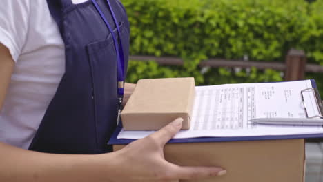 repartidora con gorra y camiseta azul con portapapeles y caja de cartón