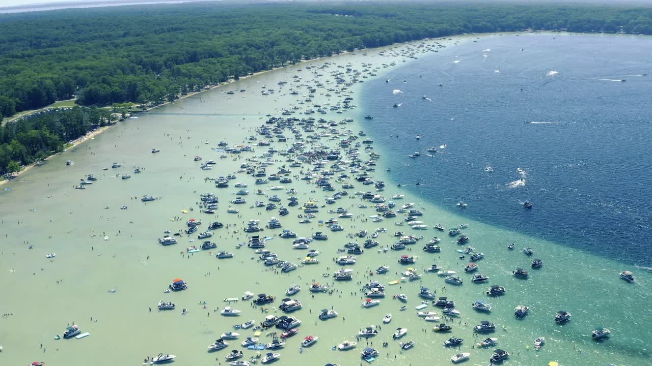 Aerial shot of Boats and Large Group People in shallow crystal clear Glacial Lake water on Sunny Summer Day Higgins Lake Michigan 4th of July