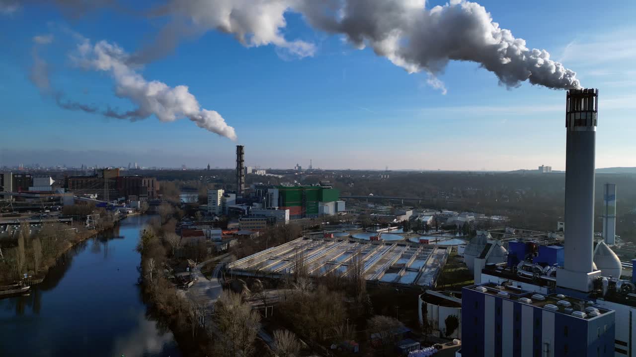 Waste to energy plant emitting smoke from its chimney, located near an urban area, environmental impact of waste. Fabulous aerial view flight drone shot footage from above
