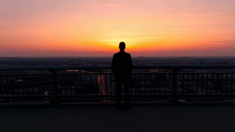 silhouette of a person overlooking a city at sunset from a rooftop