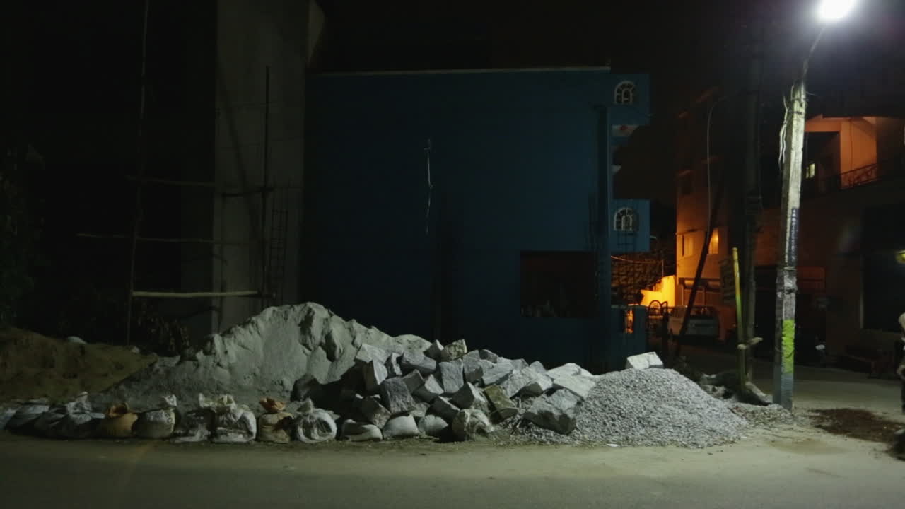 A quiet dim lighting late-night street scene with people walking and passing car motion blur in Bangalore, India