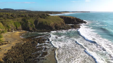 Cinematic-drone-shot-of-rocky-coast-passing-over-Kangaroos-on-a-cliff-then-revealing-ocean-waves-at-Emerald-Beach