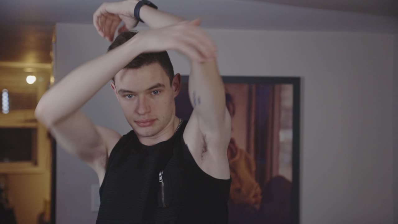 집에서 오버 헤드 삼두근 스트레칭을하고 서있는 자세에 맞는 젊은 남자