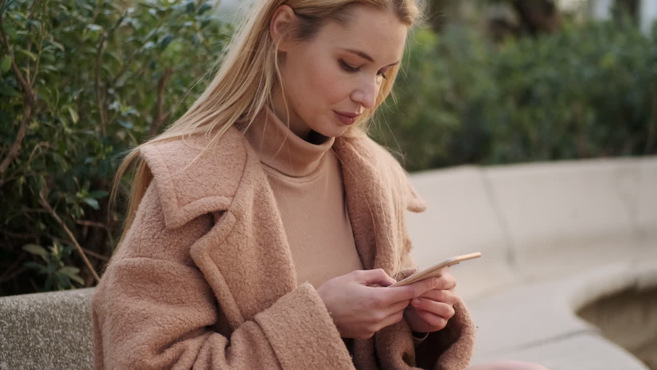 una mujer joven usando el teléfono al aire libre.
