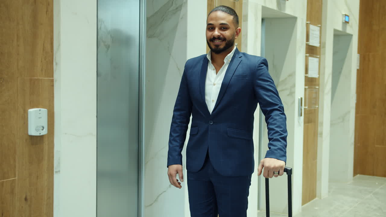 Businessman waiting for elevator with suitcase