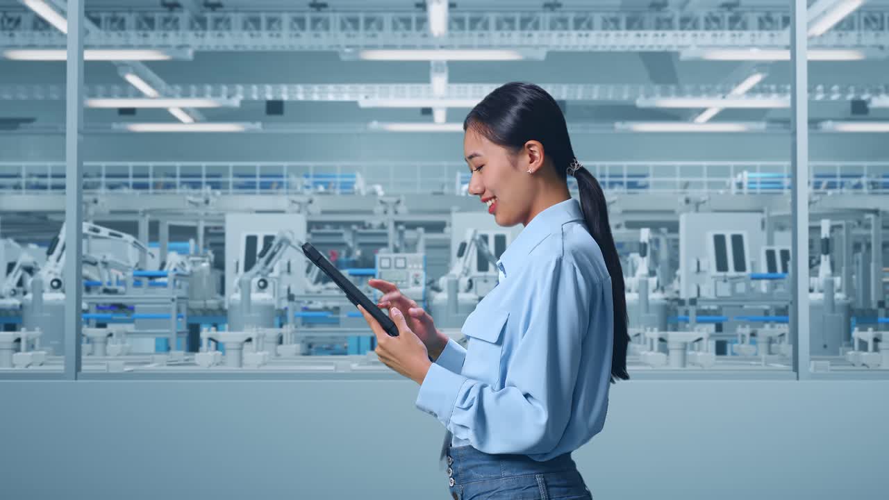 vista lateral de una trabajadora profesional asiática de pie con su tableta en la digitalización de la fábrica para un proyecto innovador, revisando su tableta con meditación