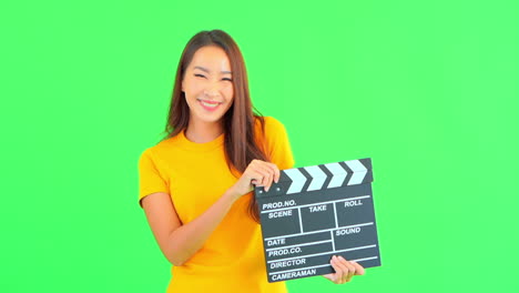 smiling asian woman with yellow t-shirt holds clapperboard