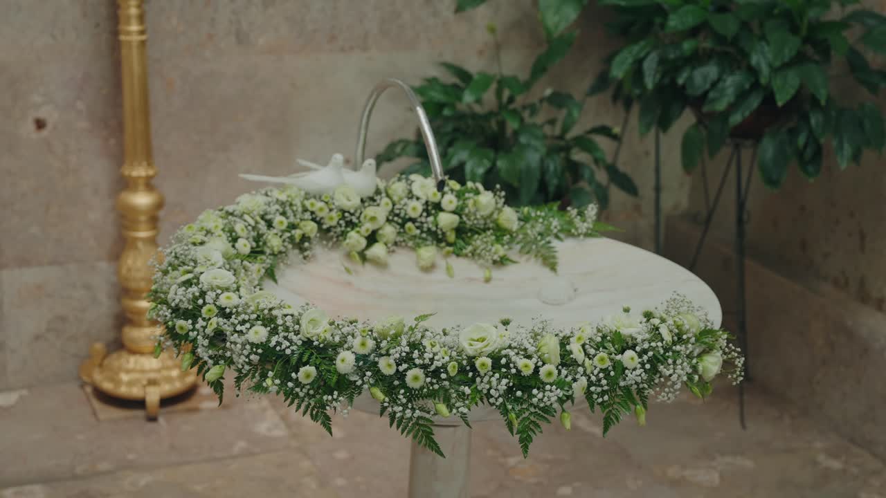 Hvit blomsteroppsats rundt døpefonten inne i kirken