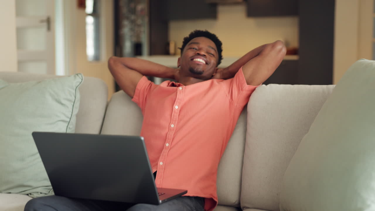 Satisfied black man, laptop and sofa in happiness