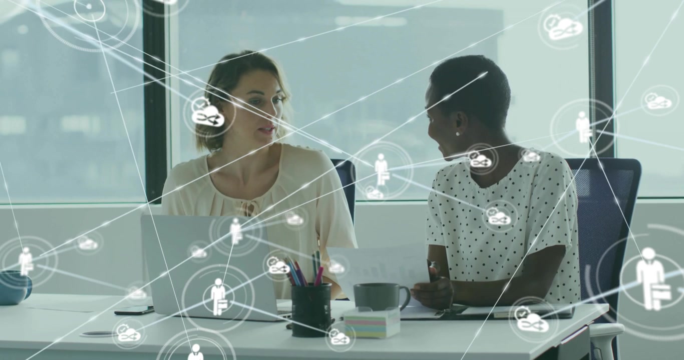 Professional women collaborating at business desk starting network icons for project planning