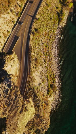 rock with tunnels for cars movement on the highway. drone footage over the road at the rocky shore of a lake tahoe, california, usa. vertical video