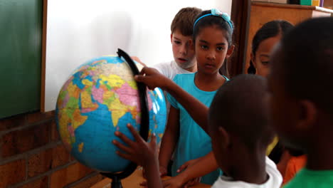 Pupils-looking-at-the-globe-in-classroom