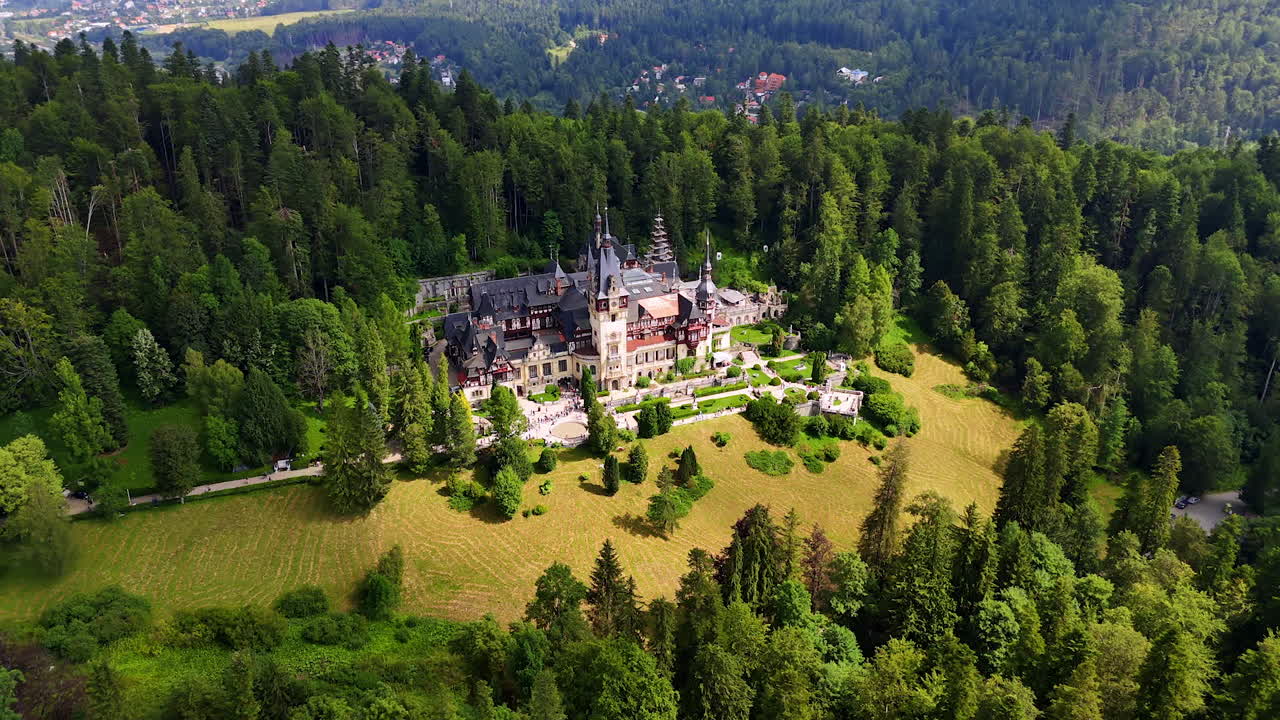 Striking scenery of the Peles Castle in the Carpathian Mountains, Romania. Lots of tourists stand in the line waiting for their turn to enter the landmark. Aerial view