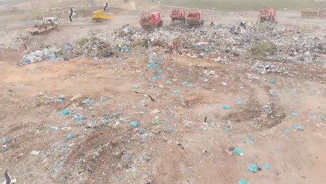 vehicles clearing rubbish piled on a landfill full of trash