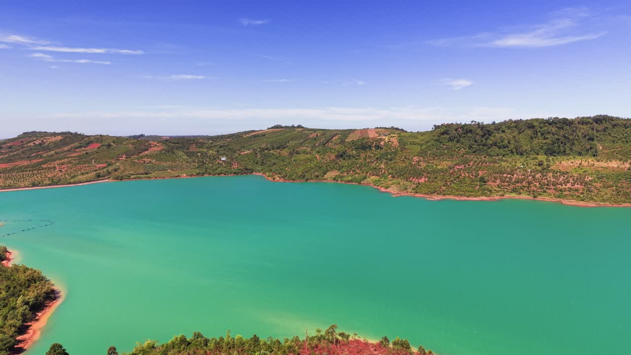 Uma vista sobre o lago em Lam Dong, Vietnã, revela água cristalina e arredores verdes. Este local destaca a beleza natural e o terreno diversificado da área durante o dia.