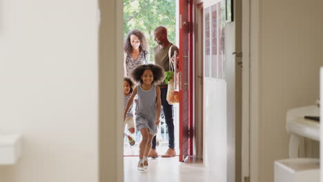 Familia-Regresando-A-Casa-Después-De-Un-Viaje-De-Compras-Usando-Bolsas-De-Plástico-Sin-Plástico-Abriendo-La-Puerta-Principal