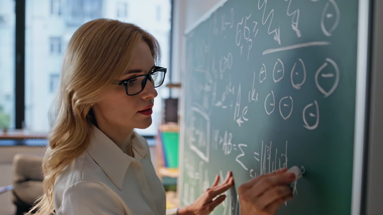 Woman tutor teaching math writing formulas at university blackboard closeup