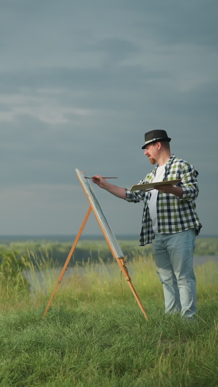 una hermosa mujer con un vestido blanco y un sombrero se mantiene en equilibrio frente a un artista, que lleva una camisa a cuadros, pantalones vaqueros y un gorro. el artista sostiene una paleta y pinta