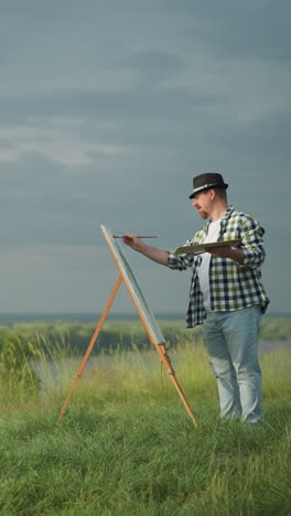 a beautiful woman in a white dress and hat stands poised in front of an artist, who is wearing a checkered shirt, jeans, and a hat. the artist is holding a palette and painting