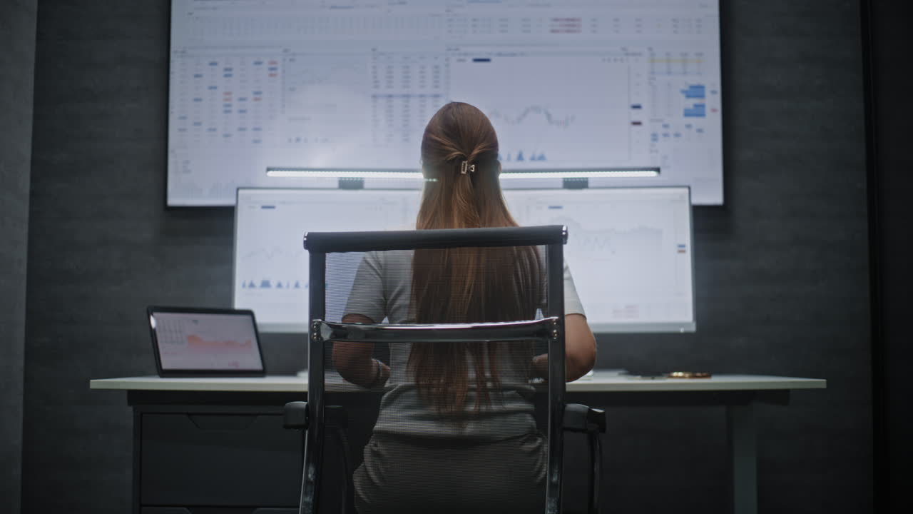 Female Financial Analyst Working on Computer with Multi-Monitor Workstation, Monitoring Real-Time Stocks and Exchange Market Charts. Successful Businesswoman in Financial Agency Office. Vertical Shot.