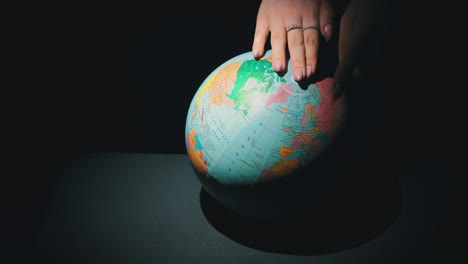 girl's hands twist the geographic globe around its axis