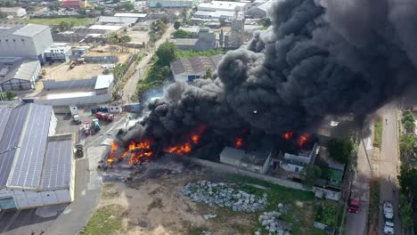 aerial drone shot over black smoke column of burning warehouse