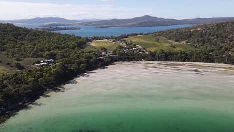 Drone-aerial-pan-sideways-over-sandy-tropical-beach-with-a-huge-lake-with-mountains-on-the-other-side