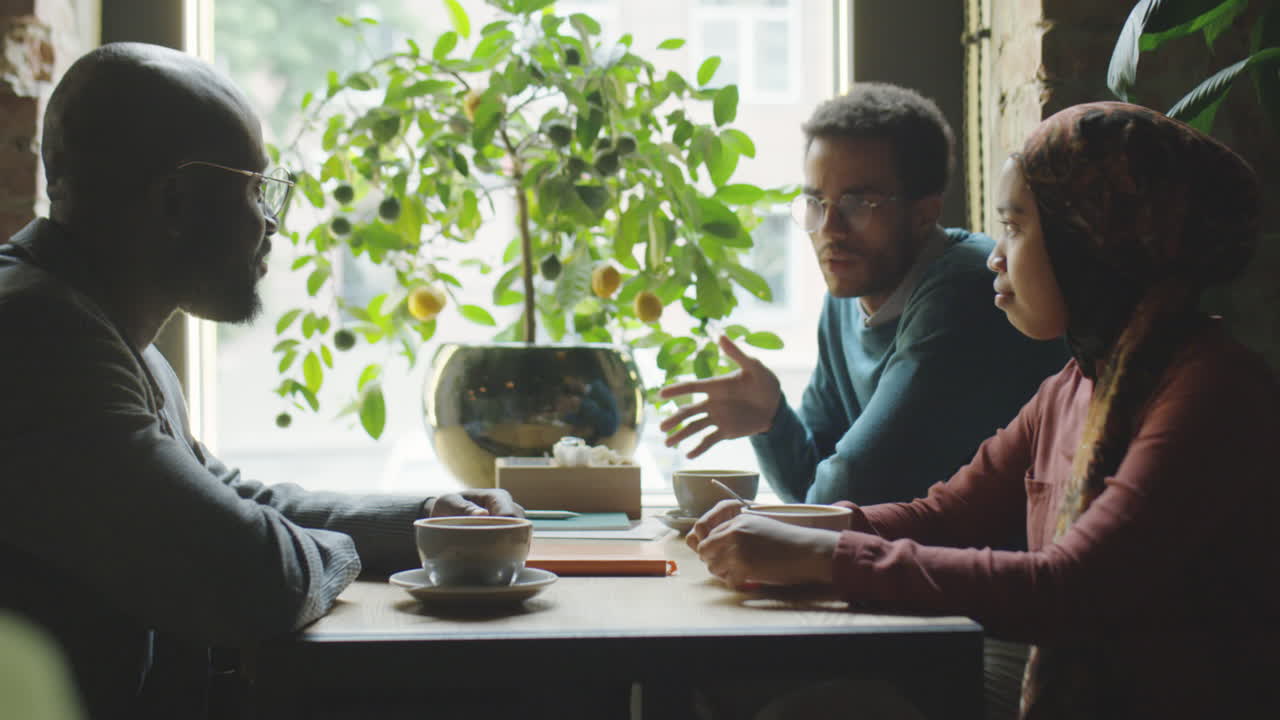 Forskellige kolleger, der snakker over en kop kaffe på en café
