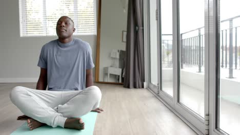 African-american-man-doing-yoga-and-meditating-at-home,-copy-space,-slow-motion