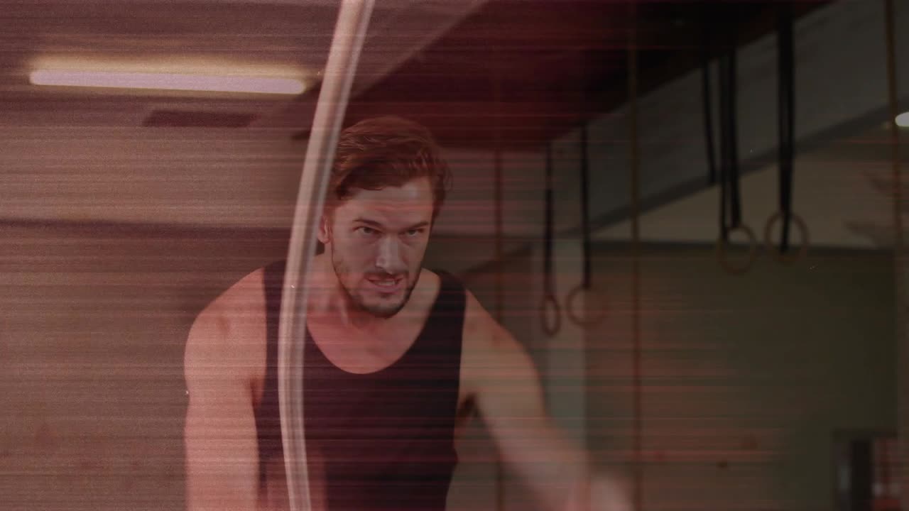 Male athlete gripping battle ropes, sending alternating arcs for fitness, ropes whipping camera