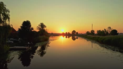 Ruhige,-Friedliche-Sonnenaufgangsdrohnenluftaufnahme-über-Einem-Reflektierenden-See-Mit-Zwitschernden-Vögeln