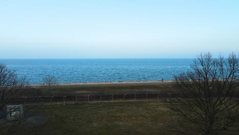 aerial view calm blue sea from a park with a person walking at promenade in the morning near westerplatte, gdansk, poland