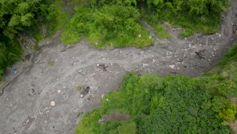 Luftaufnahme,-Kalter-Lavastrom-Des-Mount-Merapi-Und-Sichtbare-Lastwagen-Und-Sandminenarbeiter-Unterwegs