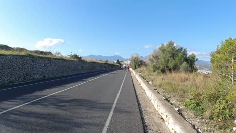 Cyclists-on-the-road-to-the-mountains,-rural-roads-in-Alicante-Spain