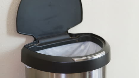 man throws away banana peel in motion sensing touchless trash can - close side