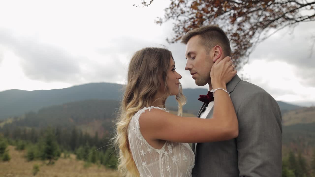 Lovely young newlyweds bride groom embracing on mountain slope, holding hands, wedding couple family
