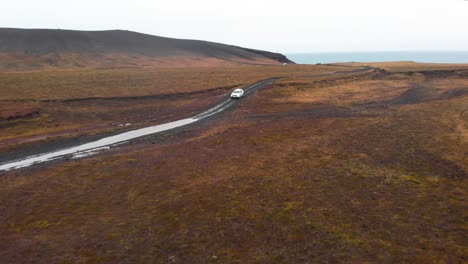 SUV-Auto-Fährt-Auf-Nasser-Schotterstraße-In-Nordischer-Landschaft-In-Richtung-Pfütze