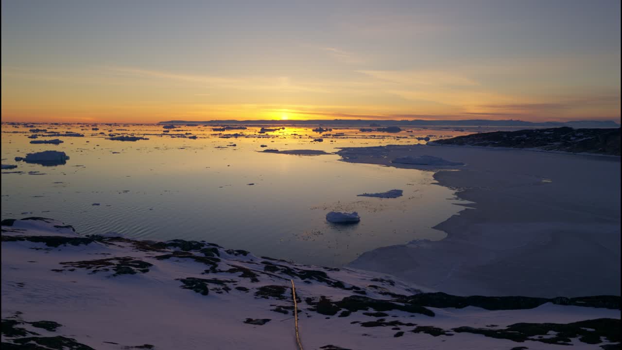 イルリサット・アイスフィヨルドの海に浮かぶ夕暮れ時の氷と雪。