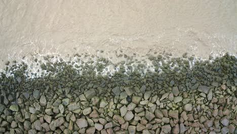 Meereswellen-Treffen-Auf-Felsen-Auf-Einem-Deich,-Stationäre-Drohnenaufnahme-über-Dem-Wasser