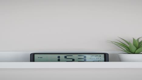 reloj digital y suculento en un estante blanco