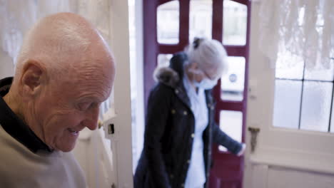 elderly man greeting nurse at door